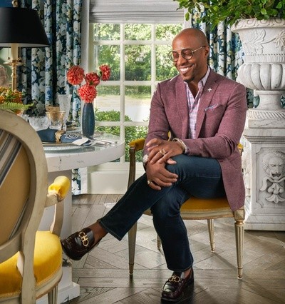 Corey Damen Jenkins sitting at a round table with yellow chairs in a business suit
