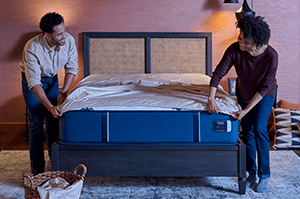 couple putting a fitted sheet on a mattress